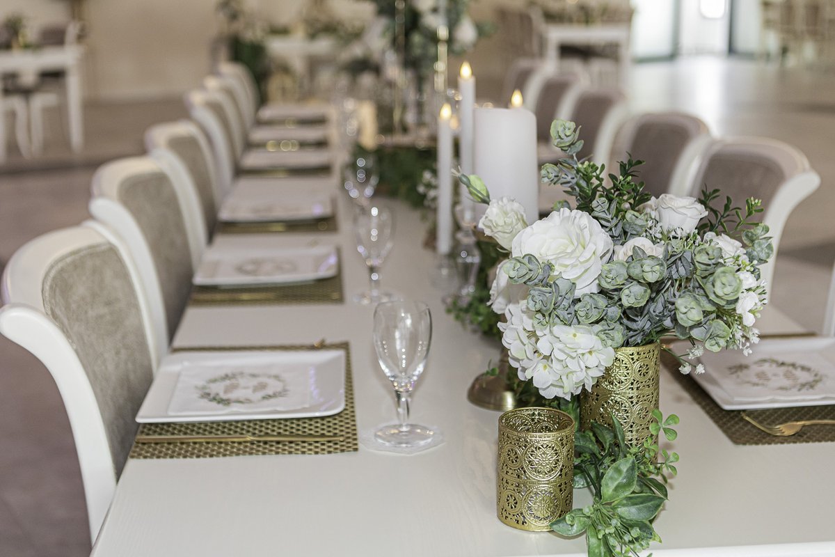 Lange Hochzeitstafel mit weißen Rosen, Eukalyptus, goldenen Windlichtern und Kerzen im Villa Restaurant Sömmerda