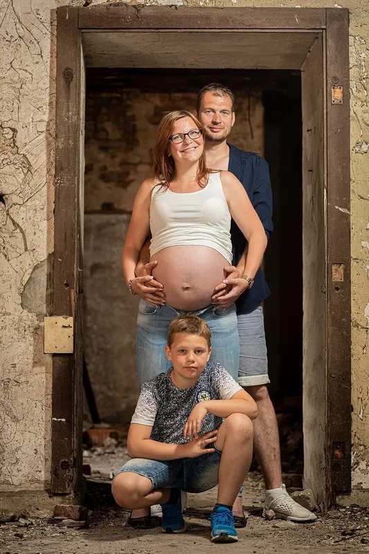 Werdende Eltern und ihr Sohn posieren in einem alten verwitterten Türrahmen, beide halten den freien Babybauch der Mutter, Babybauch Shooting Sömmerda Dirk Dittrich