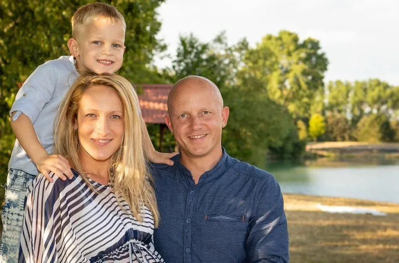 Junge lehnt sich von hinten an die Schultern seiner Mutter, daneben der Vater, im Hintergrund ein See in der Abendsonne, Familienfotograf Sömmerda Dirk Dittrich