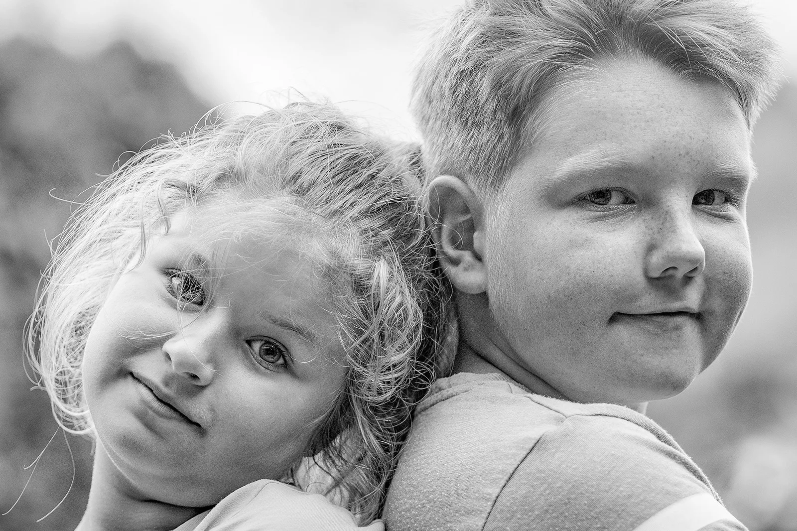Schwarzweiß-Nahaufnahme: Mädchen lehnt den Kopf an die Schulter ihres Bruders, beide schauen in die Kamera, Fotograf Sömmerda Dirk Dittrich