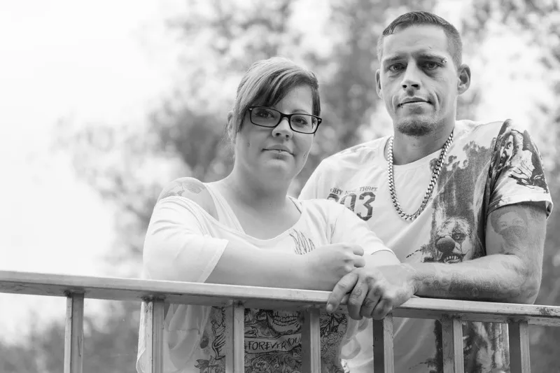 Schwarzweiß-Porträt: tätowiertes Paar lehnt an einem Metallgeländer und blickt selbstbewusst in die Kamera, Familienfotograf Sömmerda Dirk Dittrich