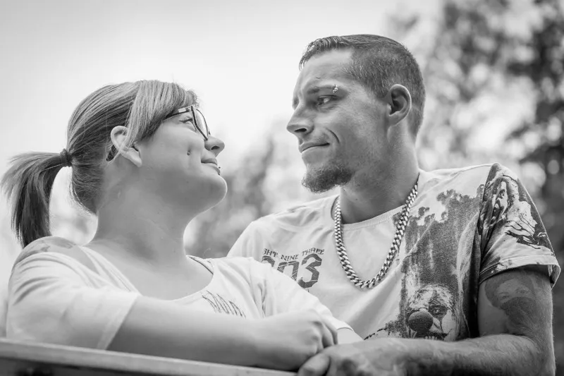 Schwarzweiß-Aufnahme: junges Paar schaut sich verliebt in die Augen, sie mit Brille und Zopf, er mit Kette und Tattoos, Familienfotograf Sömmerda Dirk Dittrich