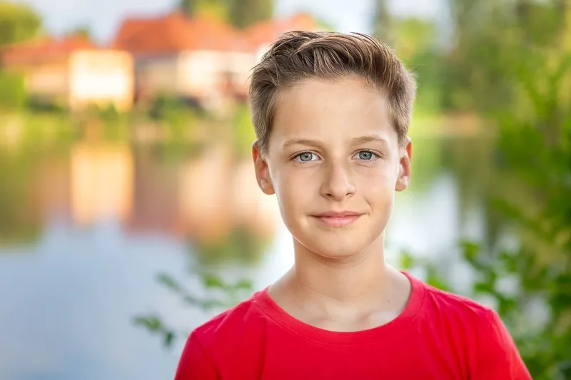 Junge im roten T-Shirt mit blauen Augen vor einem See mit Häusern im Hintergrund, Portraitfotograf Sömmerda Dirk Dittrich
