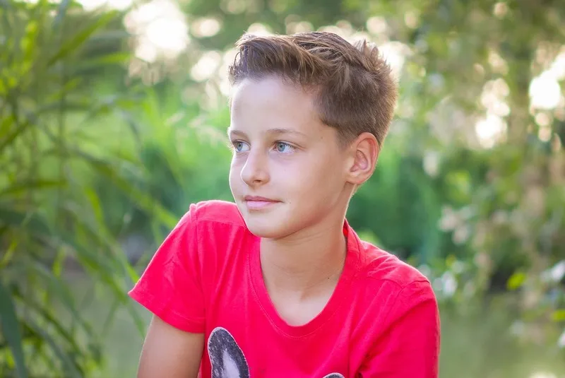 Junge im roten T-Shirt schaut zur Seite, umgeben von grüner Natur, Portraitfotograf Sömmerda Dirk Dittrich