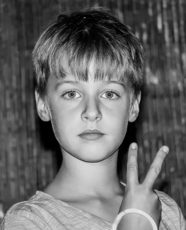 Schwarzweiß Portrait eines Jungen mit ernstem Blick, der ein Victory Zeichen zeigt, Portraitfotograf Sömmerda Dirk Dittrich