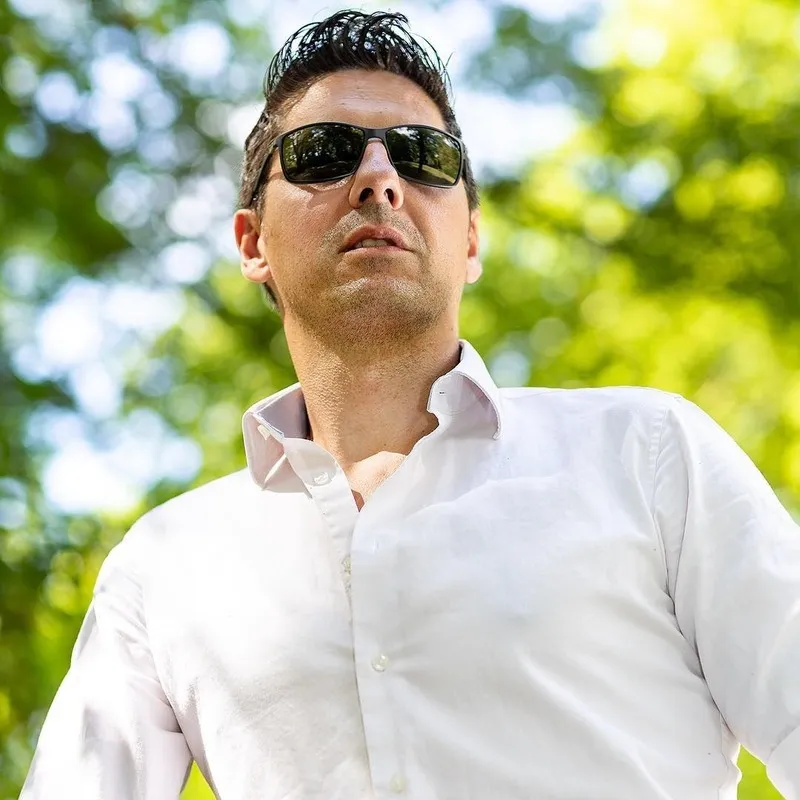 Mann im weißen Hemd mit Sonnenbrille aus der Untersicht vor grünen Baumkronen, Portraitfotograf Sömmerda Dirk Dittrich