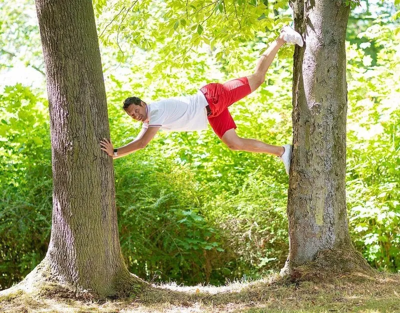 Sportlicher Mann stemmt sich waagerecht zwischen zwei Baumstämme, Portraitfotograf Sömmerda Dirk Dittrich