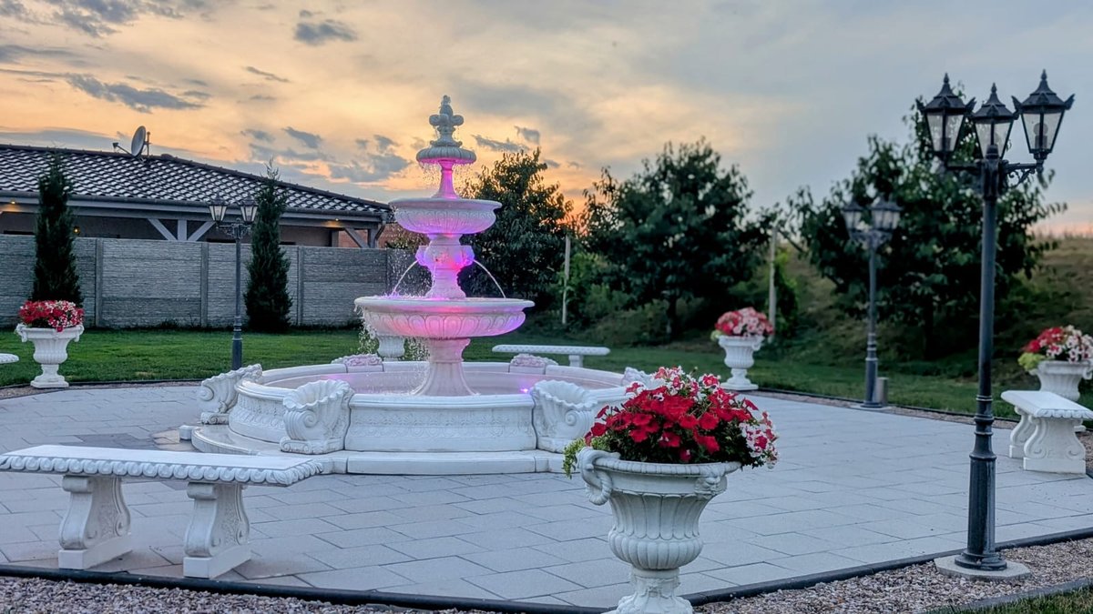 Beleuchteter Brunnen im Garten des Villa Restaurant Sömmerda im Abendlicht, mit Bänken und Laternen